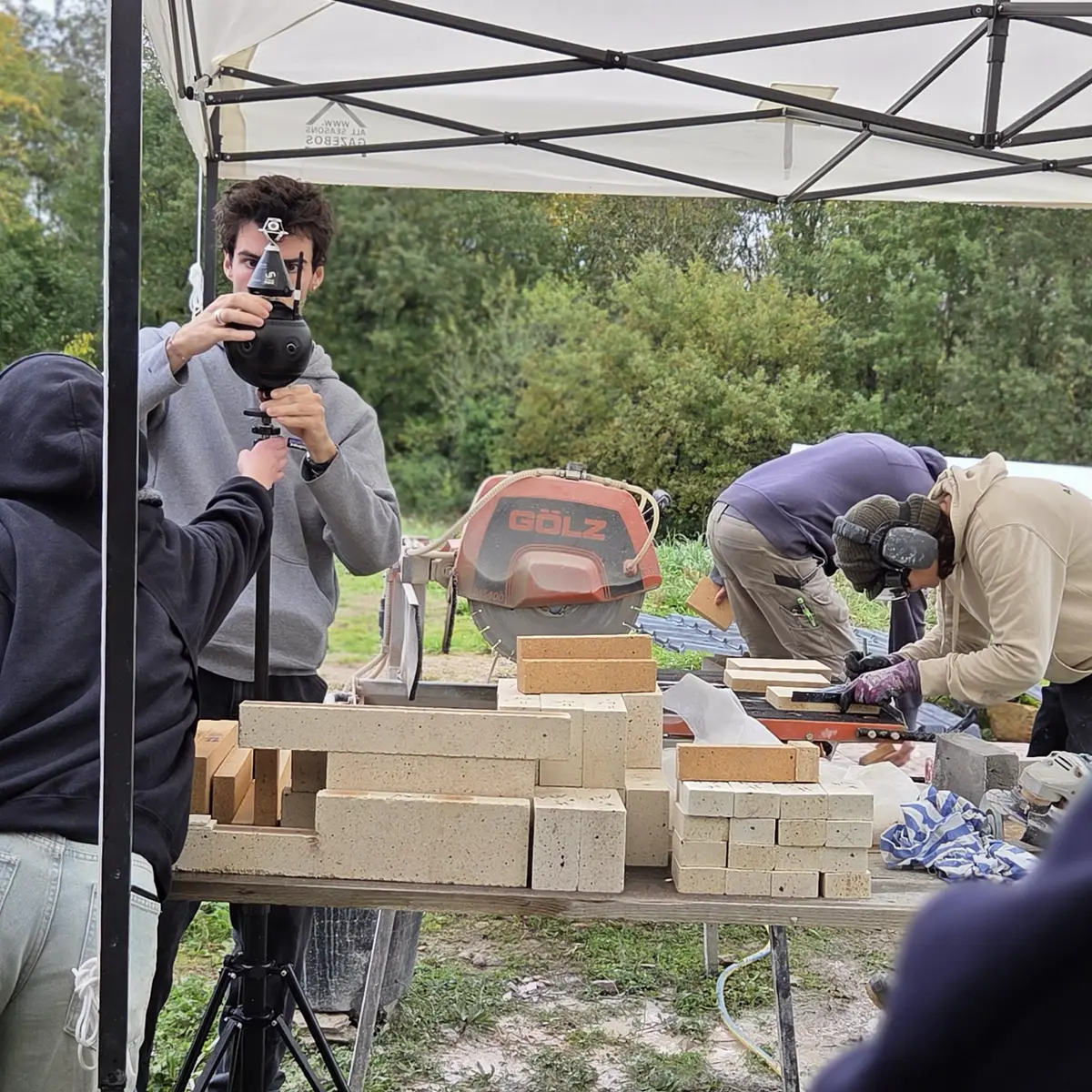 Captation à la caméra 360 sur un chantier — deux artisans travaillent la pierre à l'établi